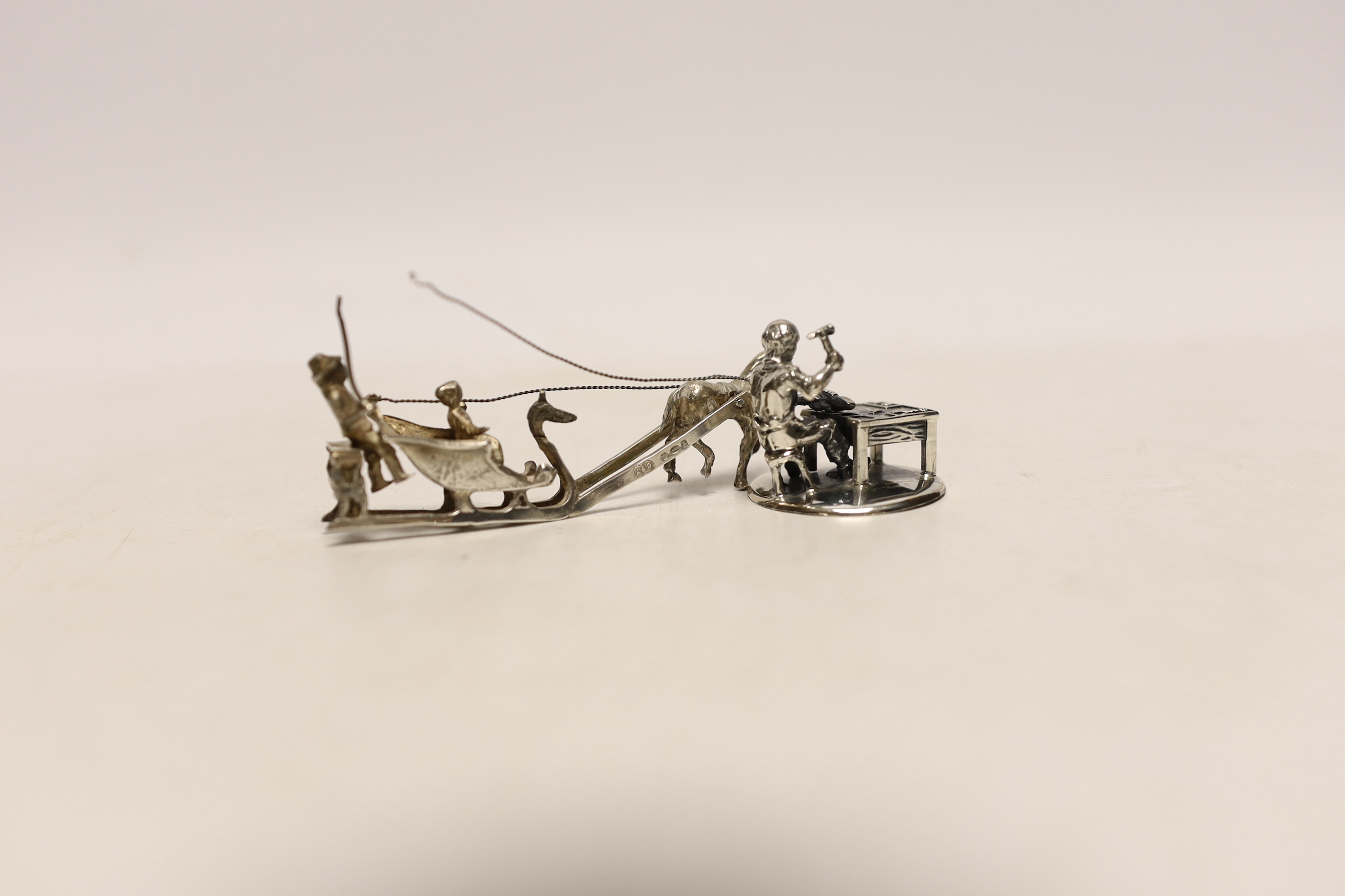 A 1920's silver miniature model of a horse drawn sleigh with figures, import marks for Adolph Barsach Davis, London, 1926, 82mm and a later Italian 925 model of a cobbler.